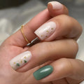 White and green press-on nails with gold foil detail