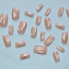 Glossy nude press-on nails featuring white abstract brush strokes and gold foil accents by Soul Struck.