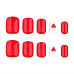 Short solid red press-on  nails with a heart accent 