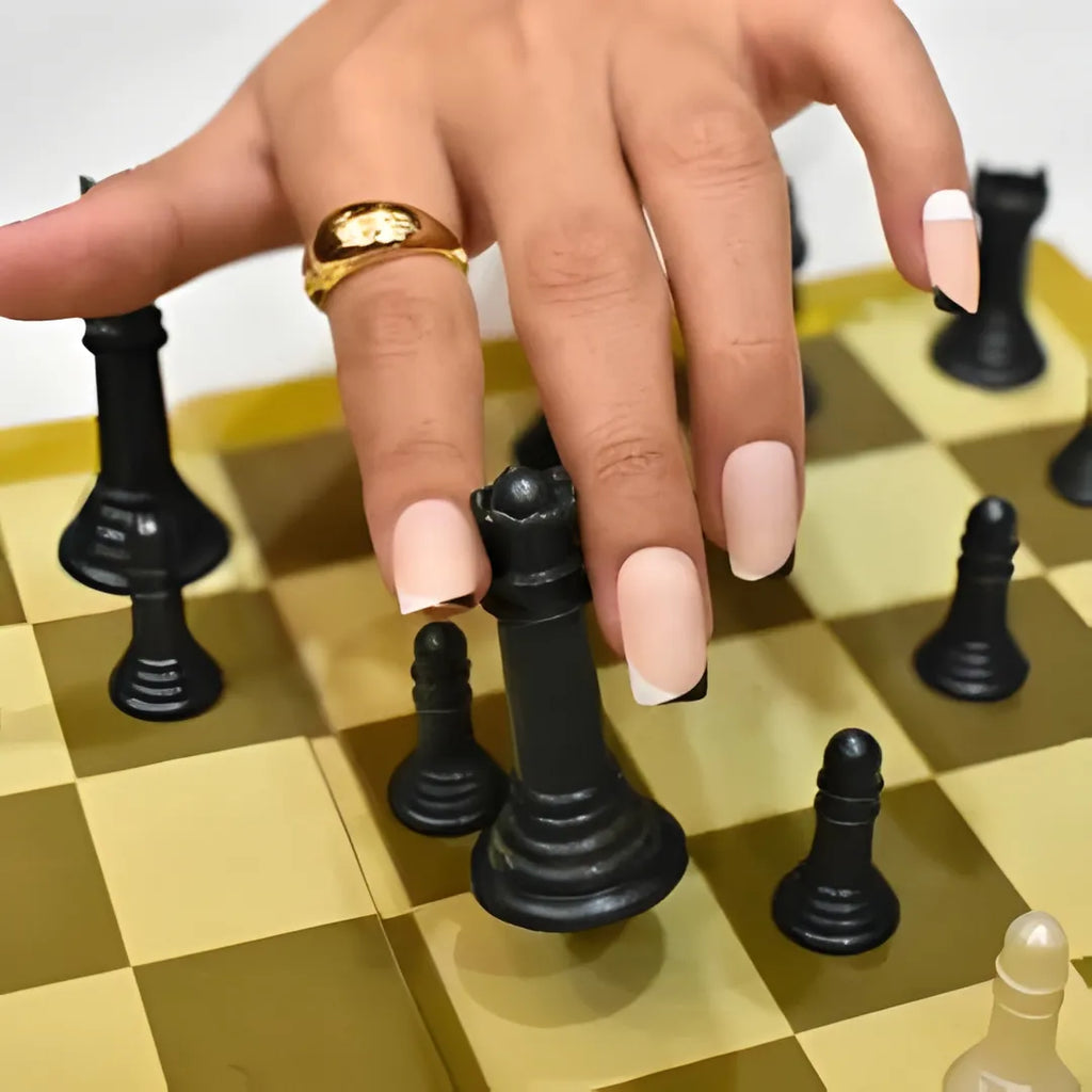 Soft pink press-on nails with contrasting black and white French tips, short square-shaped reusable fake nails and easy stick-on nail extensions for women.