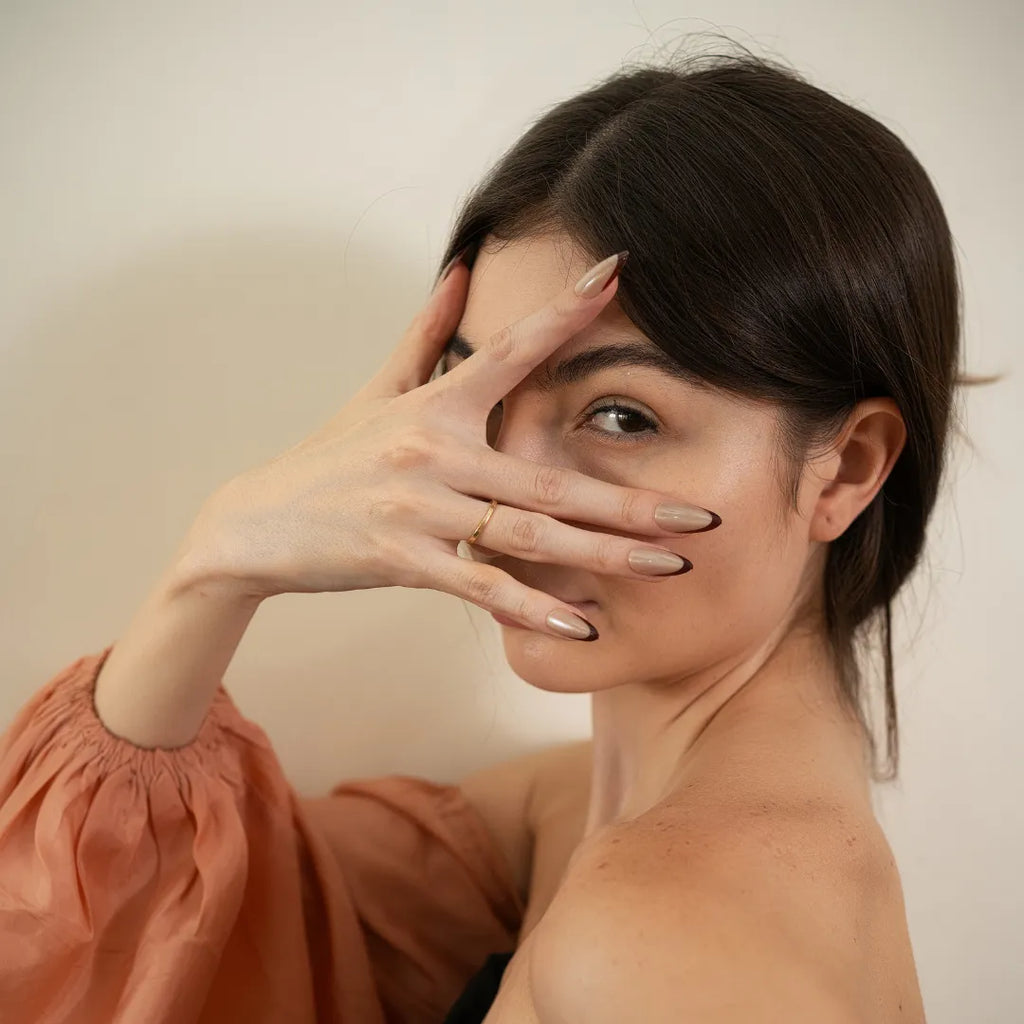 Long almond-shaped nude taupe press-on nails with dark brown angled French tips by Soul Struck