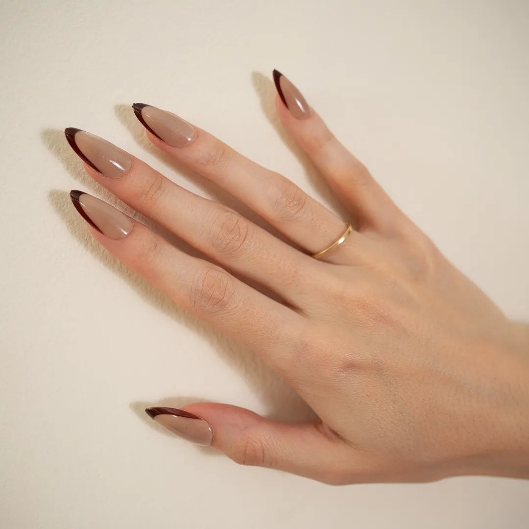 Long almond-shaped nude taupe press-on nails with dark brown angled French tips